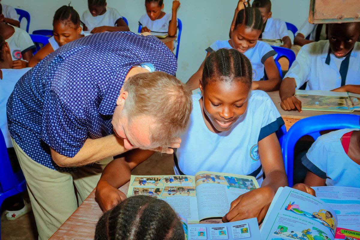 A Give To Others team member helping a student read during a classroom lesson in Kinshasa